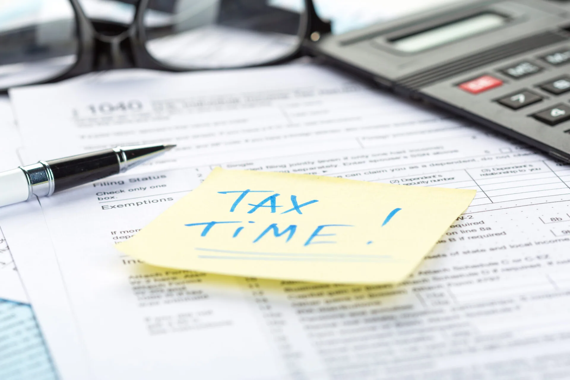 Preparing tax forms with calculator and paperwork on table for deadline approach